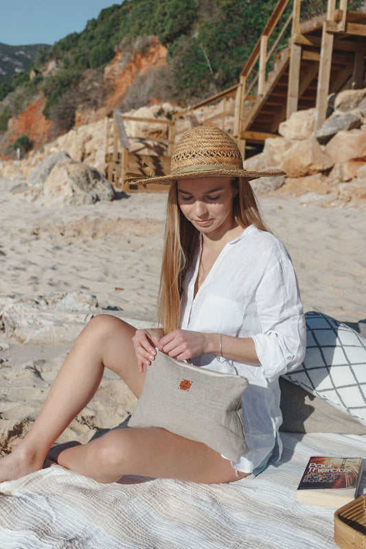 Woman at the beach wearing a linen cosmetic bag pouch with women´s essentials at the beach 