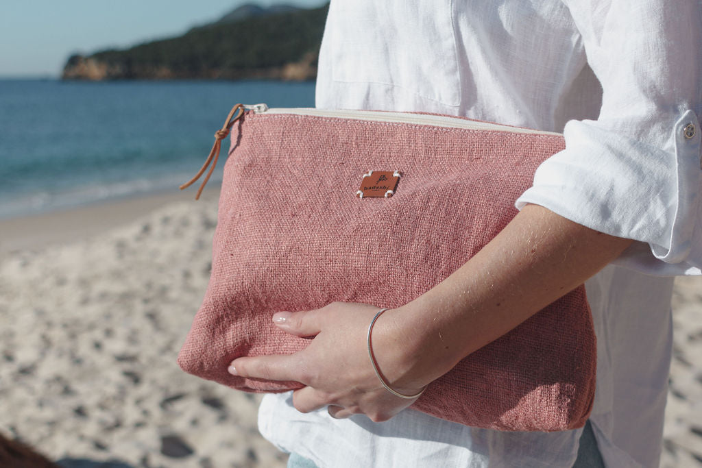 a woman at the beach wearing a 100% Linen Cosmetic bag pouch with women´s essentials at the beach