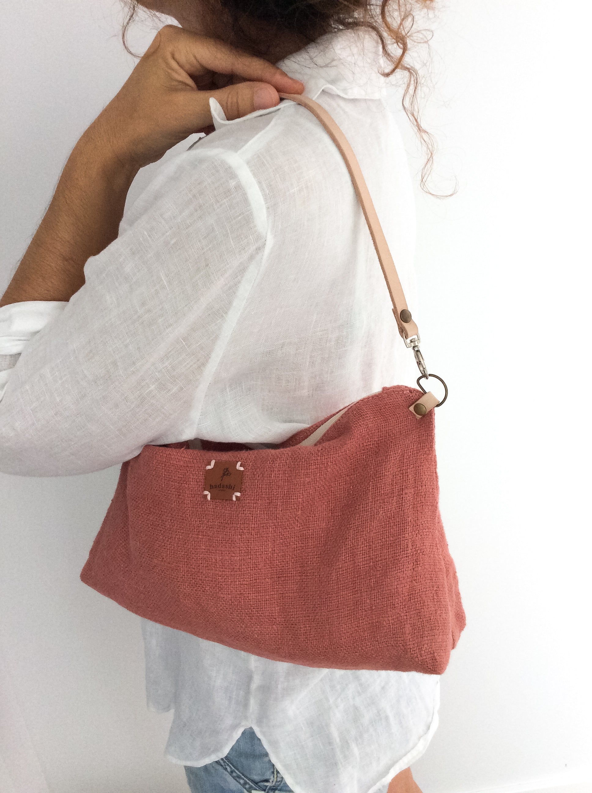 woman wearing a white linen shirt and a linen slouchy pouch in rose with a thin leather strap